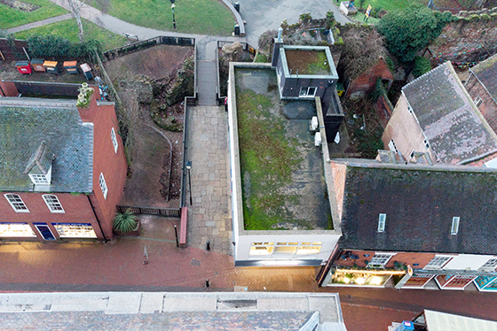 An aerial view with a building on the left, a pathway in the middle and then more buildings on the right