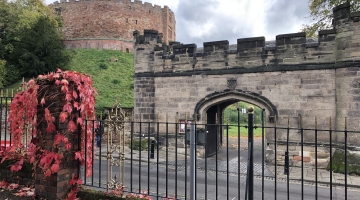 photo of a old turret building and archway with a castle in the background