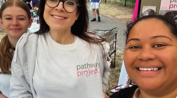 three smiling people outside by pop up banners